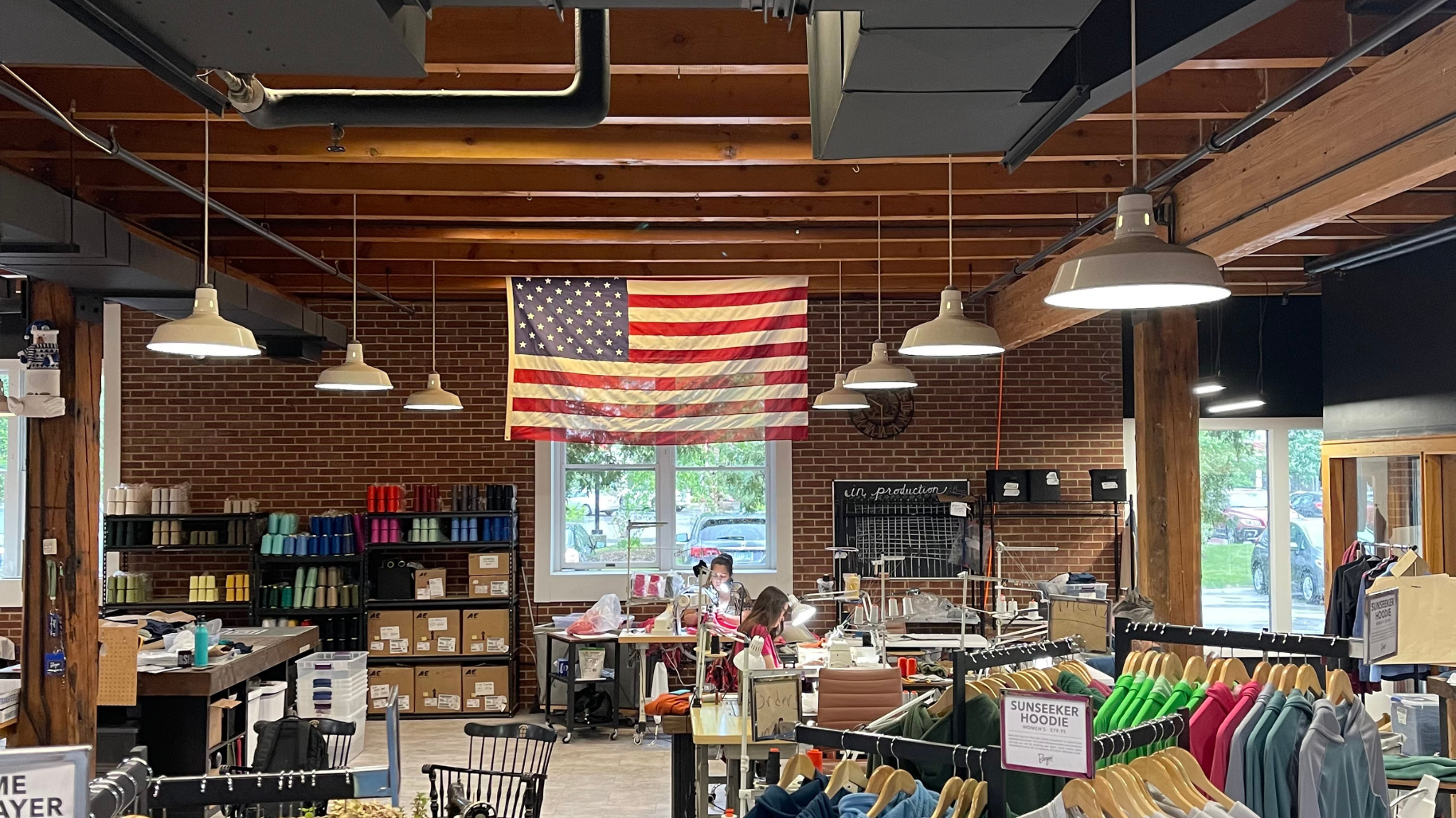 Burgeon Outdoor's retail floor. Apparel is seen hanging on racks and the American flag is in the background.