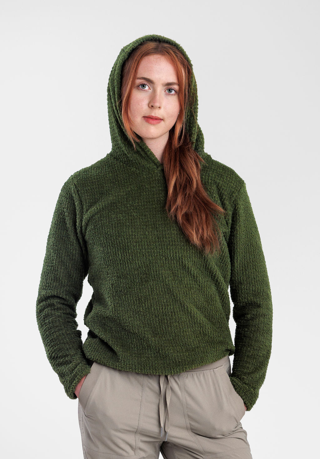 A woman wearing a Alpha 120 Hoodie and light beige drawstring pants, standing against a plain light gray studio background.