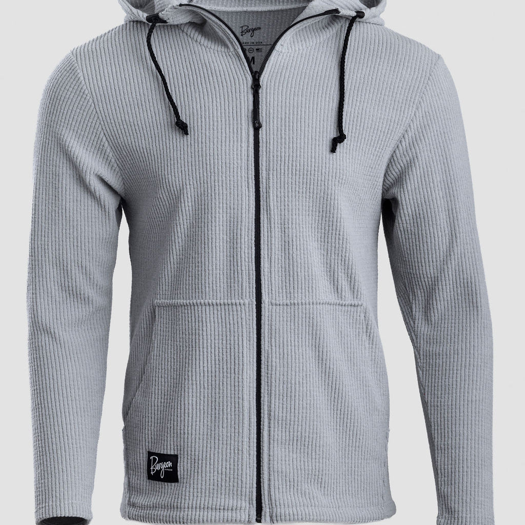 A light gray ribbed zip-up hoodie with black drawstrings and a black zipper, shown on a neutral light gray background.