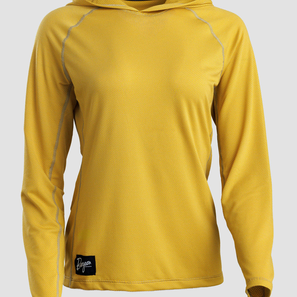 A yellow long-sleeve sun hoodie with a textured mesh fabric, shown on a neutral light gray background. It features a black brand patch near the bottom hem and a black logo strip on the inside of the hood.