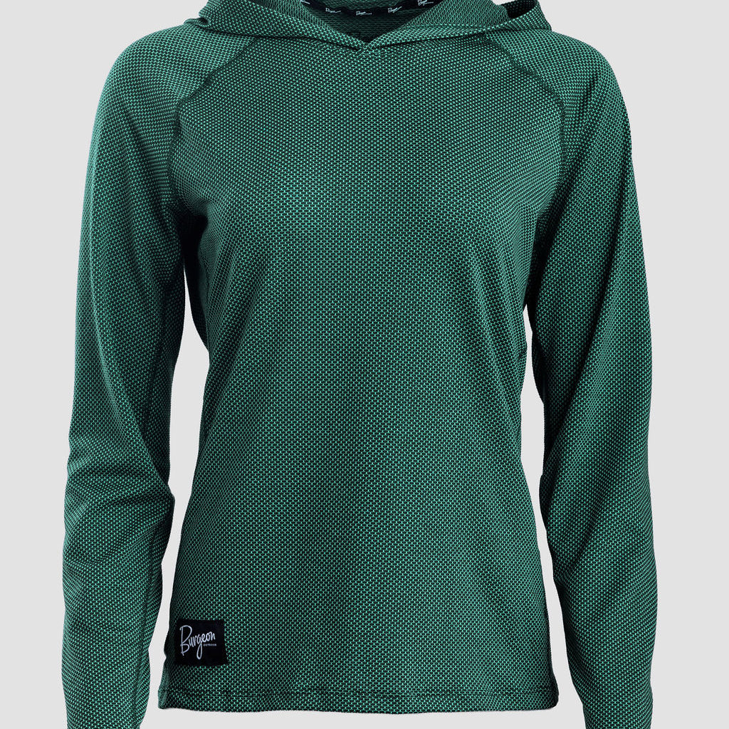 A dark green long-sleeve sun hoodie with a textured, mesh-like fabric, shown on a neutral light gray background. A small black brand patch is visible on the bottom left hem.