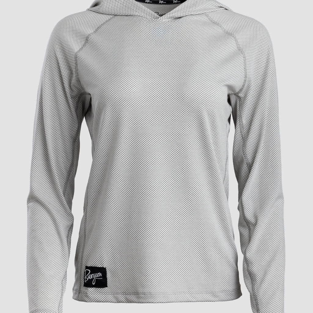 A light gray long-sleeve sun hoodie with a subtle textured pattern, featuring a black brand patch on the lower left hem and a black patterned inner neck label.