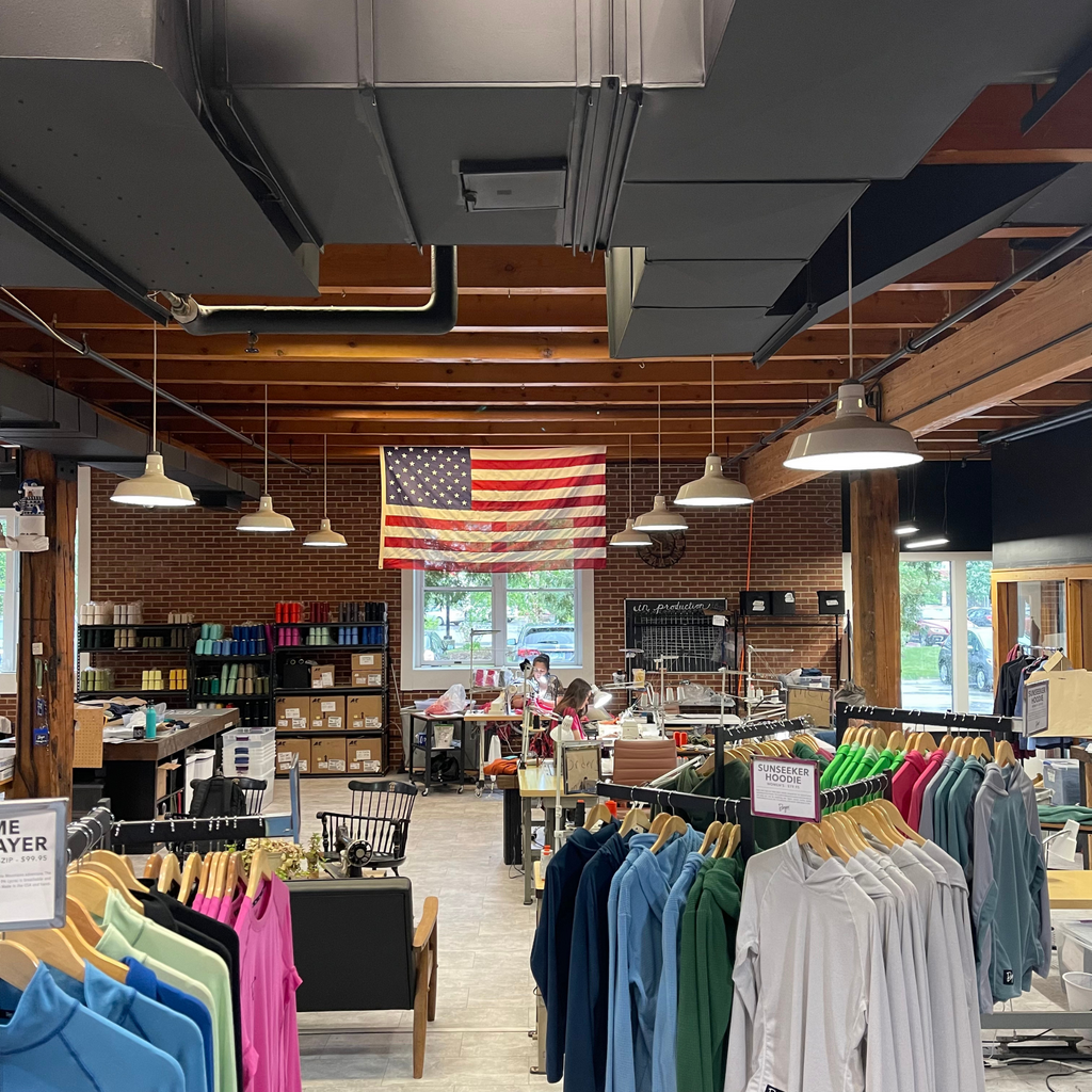 Burgeon Outdoor's retail floor. Apparel is seen hanging on racks and the American flag is in the background.