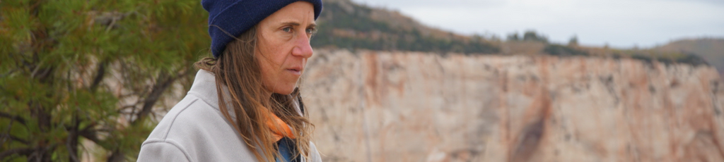 A female hiker looks ahead while wearing a Campfire 1/2 Zip in 'Gray.'
