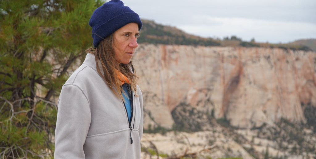 A female hiker looks ahead while wearing a Campfire 1/2 Zip in 'Gray.'