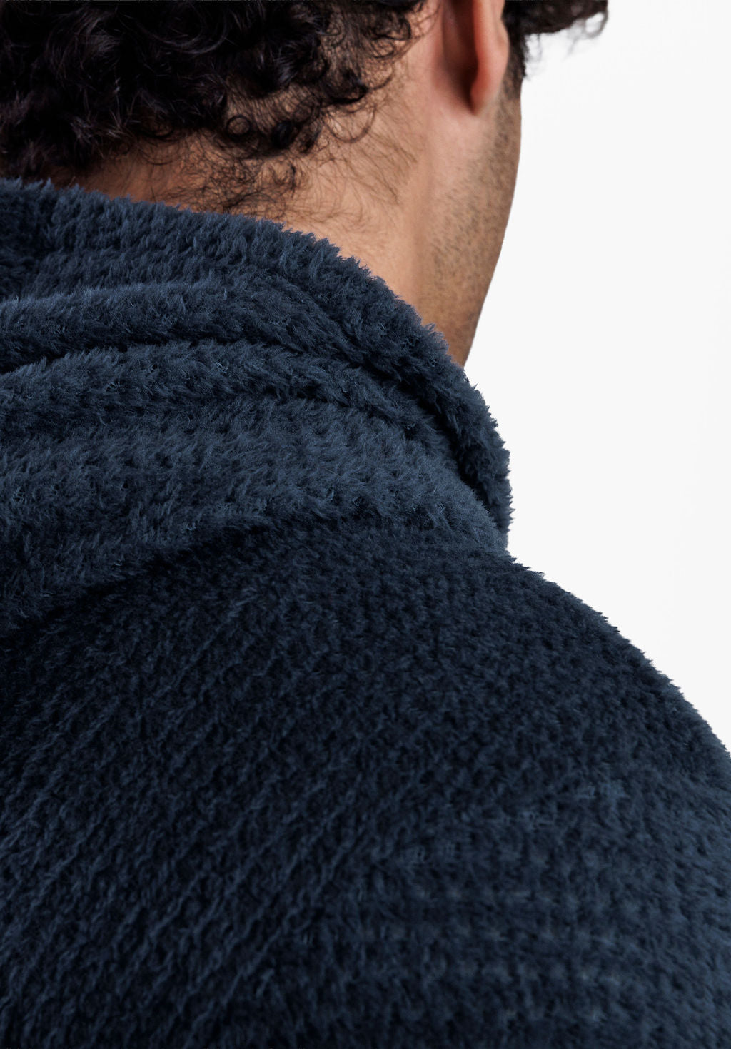 Close-up of a person wearing a dark navy Alpha 120 hoodie, showing the back of the head, neck, and shoulder against a plain gray background.