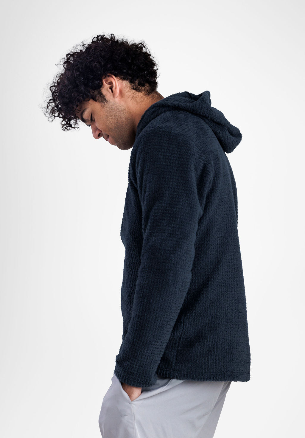 A man in profile wearing a dark navy Alpha 120 hoodie and light gray pants, photographed against a clean white studio background.