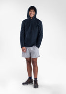 A man wearing a dark navy Alpha 120 hoodie, light gray athletic shorts, and dark running shoes, standing against a plain white studio background.
