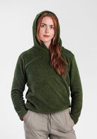 A woman wearing a Alpha 120 Hoodie and light beige drawstring pants, standing against a plain light gray studio background.