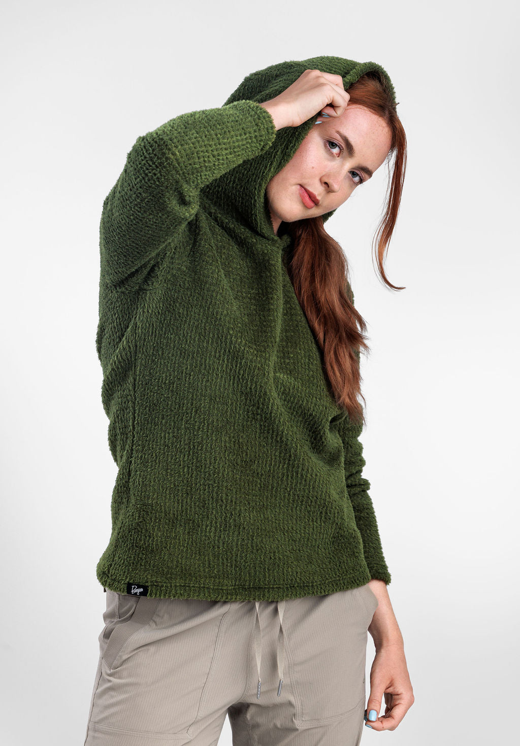 A woman wearing a Alpha 120 Hoodie  and light beige pants, posing against a plain white studio background.