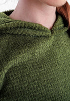 Close-up of a person wearing a Alpha 120 Hoodie , showing the neck, collar, and part of the shoulder against a light neutral background.
