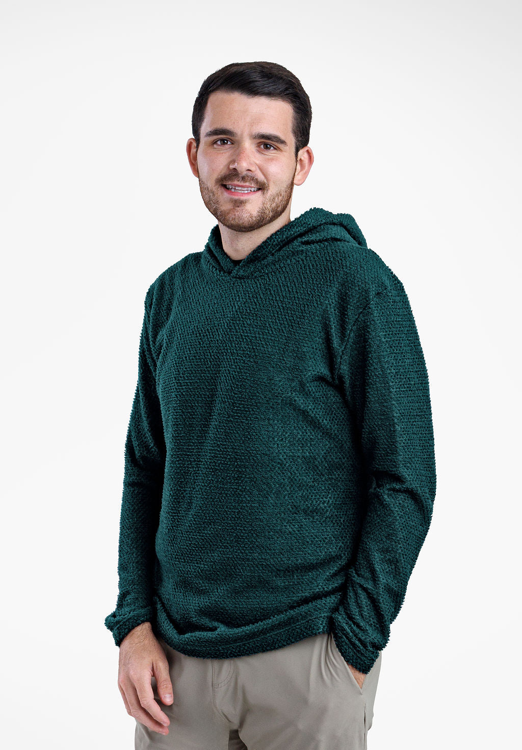 A man wearing a dark green textured Alpha 90 hoodie and light gray pants, standing against a plain white studio background.