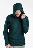 A man wearing a dark green textured Alpha 90 hoodie, posing with the hood up against a plain white background.
