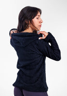 A woman wearing a black Alpha 90 hoodie, shown from the back and side against a plain gray studio background.