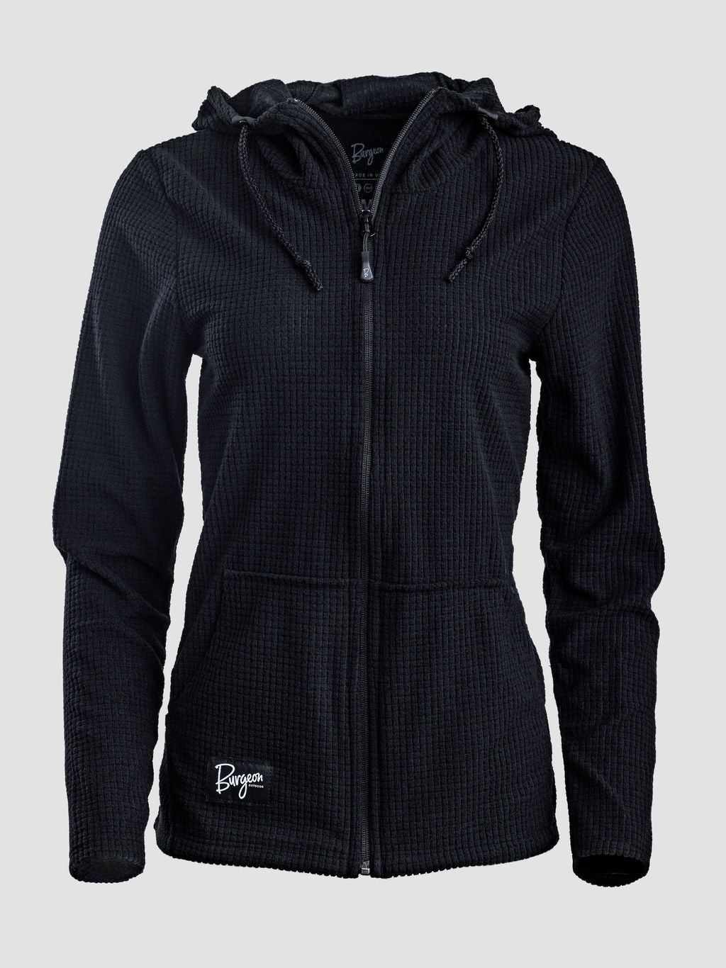 A black waffle-knit zip-up hoodie with a drawstring hood and a small white embroidered logo on the lower left front, shown against a light gray background.