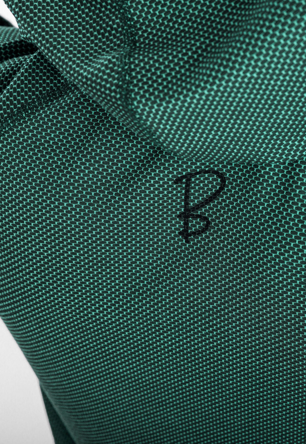 Close-up of a dark green Sunseeker Hoodie fabric with a small black letter 'B' logo.