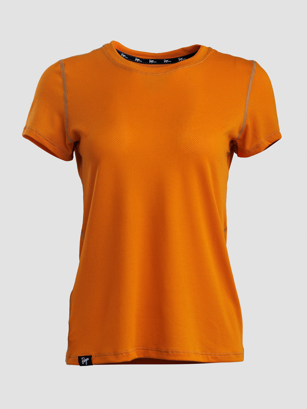 An orange short-sleeve crewneck athletic t-shirt with subtle gray piping details along the shoulders and a small black logo patch near the bottom hem, displayed on a neutral light gray background.