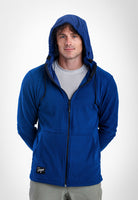 A man wearing a royal blue Highlander zip-up hoodie with a black zipper and black drawstrings, layered over a light gray t-shirt and paired with gray pants, photographed against a light gray studio background.