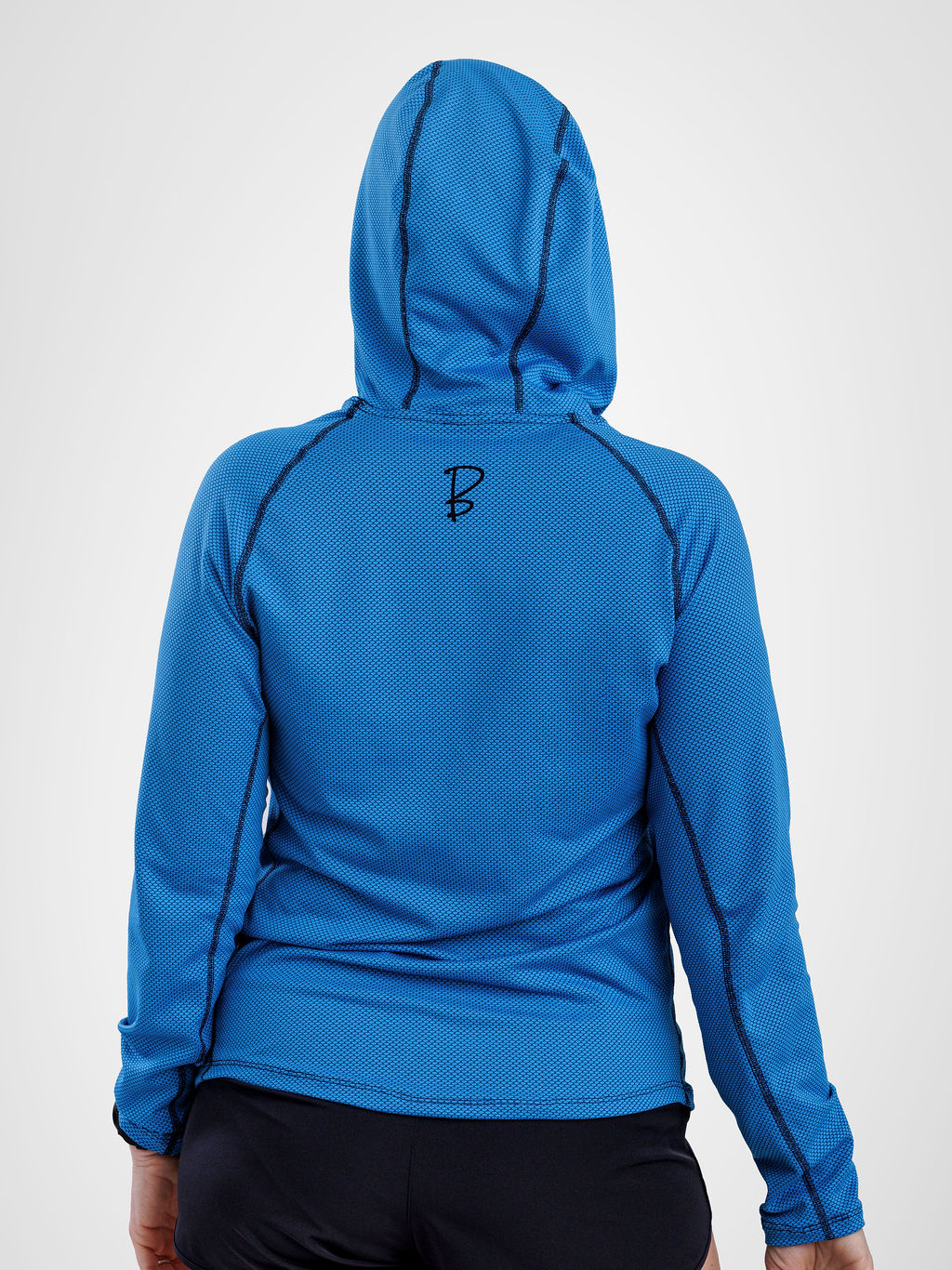 A person shown from the back wearing a bright blue long-sleeve sun hoodie with black contrast stitching and a small black monogram logo near the upper back, against a light gray studio background.