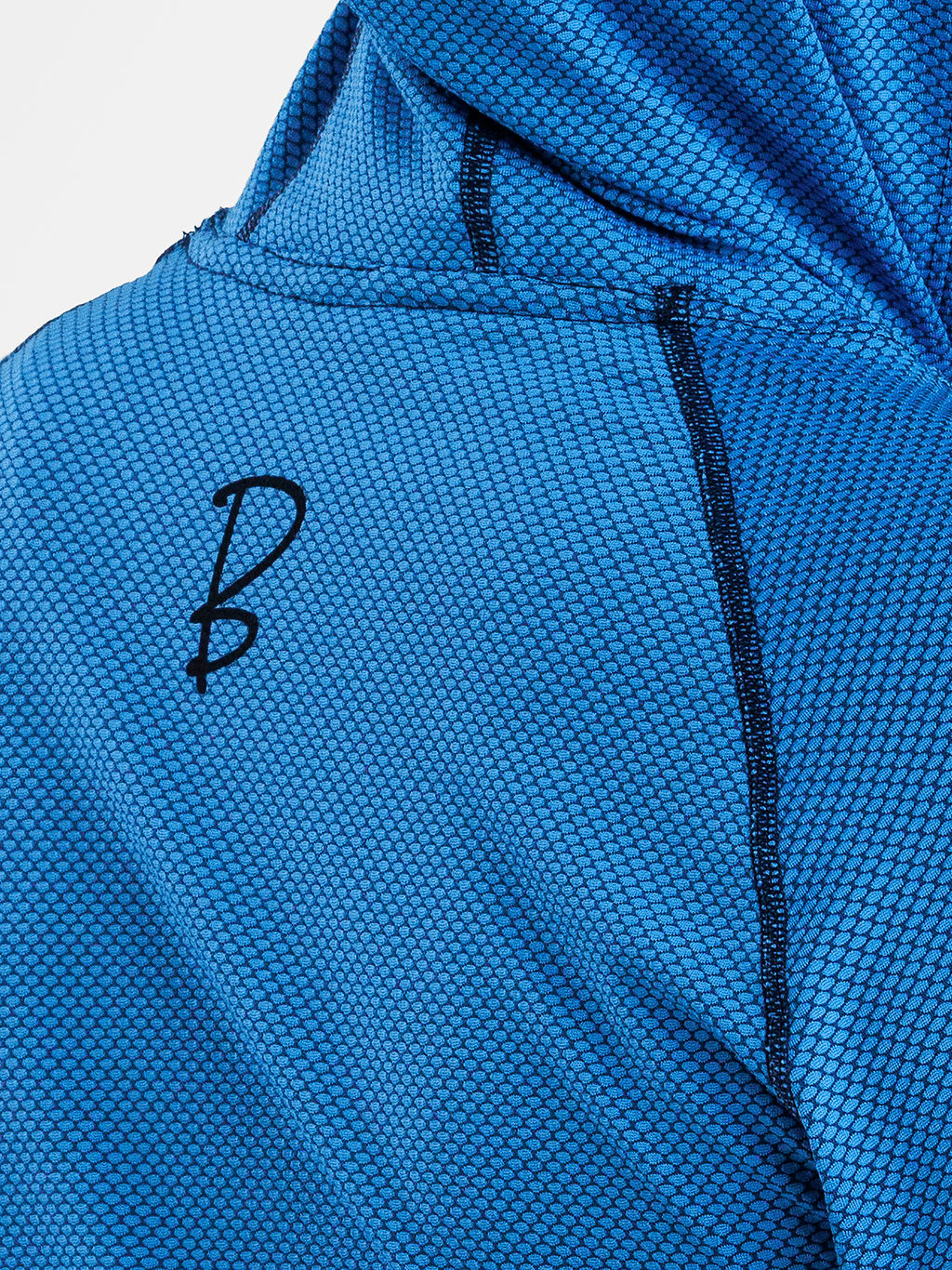 Close-up of a blue textured sun hoodie with a black embroidered stylized 'B' logo on the chest and black piping along the shoulder seam.