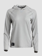 A light gray long-sleeve sun hoodie with a subtle textured pattern, featuring a black brand patch on the lower left hem and a black patterned inner neck label.