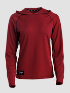 A women's long-sleeve sun hoodie in a deep red or burgundy color, featuring a textured mesh fabric and a small black brand patch near the bottom hem, shown against a light gray background.