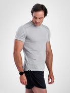A man wearing a light gray athletic short-sleeve t-shirt and black athletic shorts, standing against a light gray studio background.