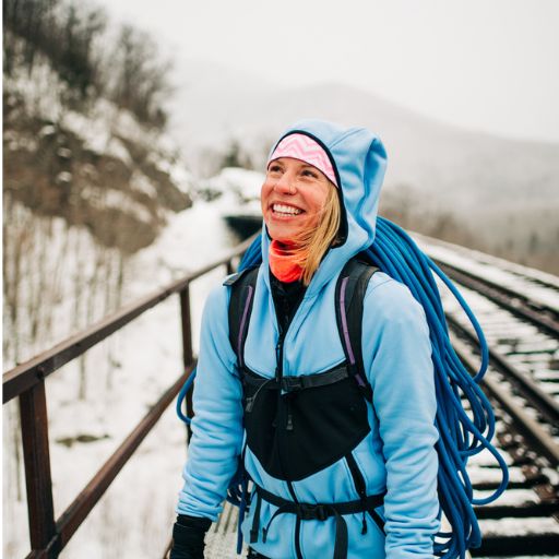 Female hiker wearing the Women's Washington Outer Layer in Classic Blue looking upwards.